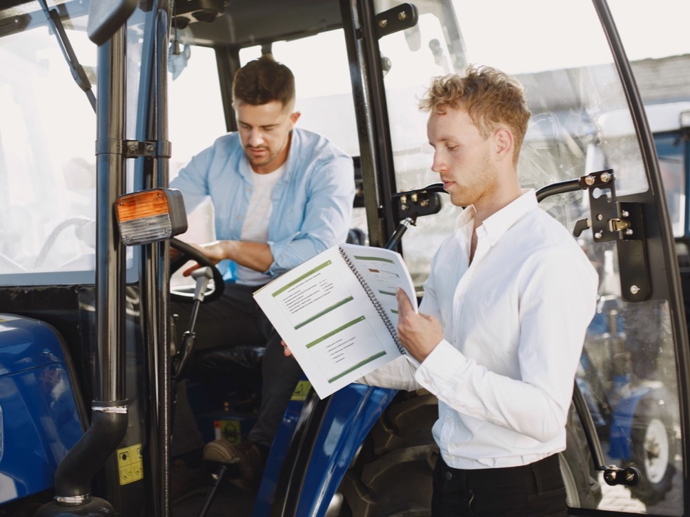 Imagem de capa de dois homens lendo o manual de uma máquina agrícola